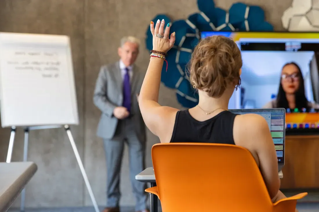 Person holding their hand up in a classroom.